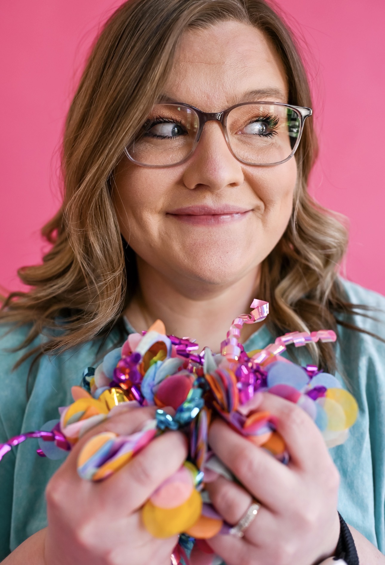 Shelb holding a handful of colorful confetti, smiling